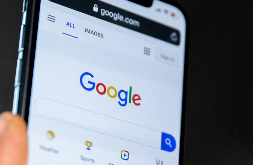 A close-up of a smartphone screen displaying the Google search homepage with the logo visible. The image captures the concept of local search visibility and the importance of appearing in search results to reach customers.