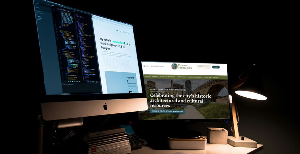 A wide-angle interior view of a professional Minneapolis home office studio featuring an organized workspace with an iMac, a secondary monitor, and minimalist design elements against a clean, light-colored wall.